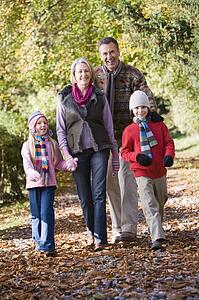 Grandparents walking with grandchildren outdoors in park and smiling