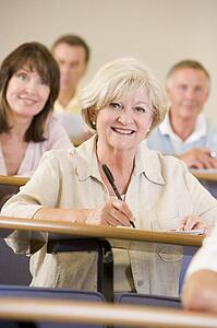 Woman sitting in adult classroom with students in background (selective focus)