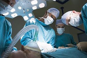 Three Surgeons Operating On A Patient