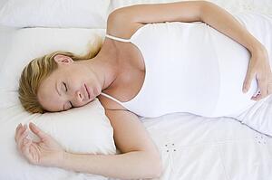 Pregnant woman lying in bed sleeping