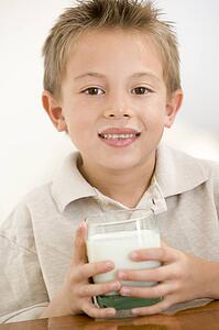 Young boy indoors drinking milk smiling