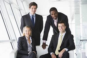 Four businesspeople in office lobby smiling
