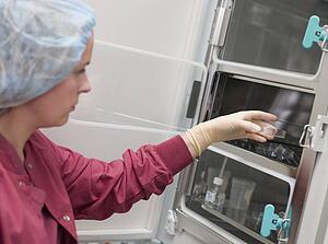 Embryologist putting sample into incubator (selective focus)
