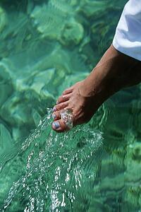 Woman's foot outdoors dipping into water (selective focus)