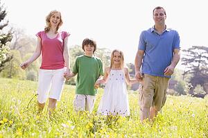 Family walking outdoors holding flower smiling