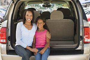 Woman with young girl sitting in back of van smiling