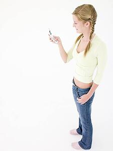 Teenage girl holding cellular phone and smiling