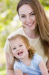 Mother holding daughter outdoors smiling