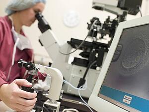 Embryologist with microscope performing an intra cytoplasmic sperm injection (selective focus)