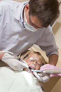Dentist in exam room with young boy in chair