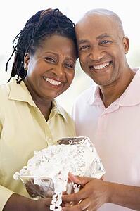 Husband and wife holding gift smiling