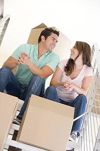 Couple sitting on staircase with boxes in new home smiling