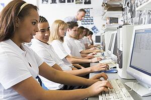 Students working on computer workstations with teacher