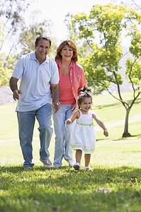 Grandparents walking in park with granddaughter