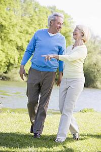 Couple walking outdoors at park by lake smiling
