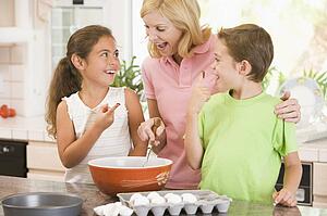 Woman and two children in kitchen baking and smiling