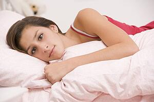 Teenage Girl Lying On Her Bed Looking Sick 