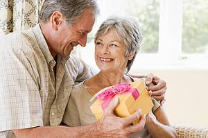 Husband giving wife gift in living room smiling