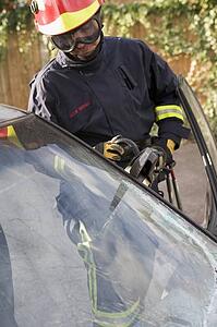 Firefighter cutting out a windshield after an accident