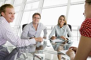 Four businesspeople in a boardroom with paperwork smiling
