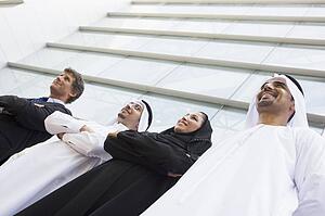 Four businesspeople standing outdoors by building smiling (selective focus)