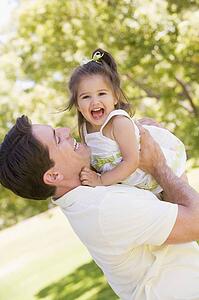 Father holding daughter outdoors smiling
