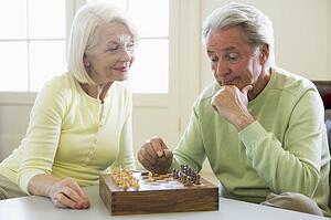 Couple playing chess in living room smiling
