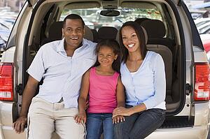 Family sitting in back of van smiling