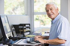 Man in home office using computer smiling