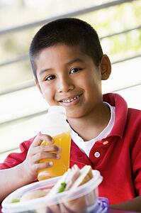 Student outdoors with lunch drinking juice (selective focus)