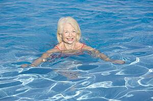 Woman swimming in outdoor pool smiling