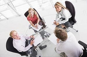 Four businesspeople in boardroom with paperwork smiling