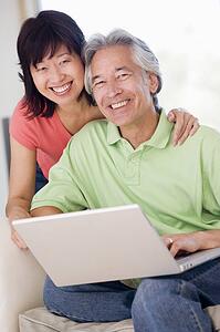 Couple in living room with laptop smiling