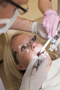 Dentist and assistant in exam room with woman in chair