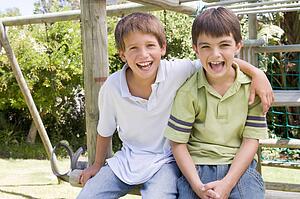 Two young male friends at a playground smiling