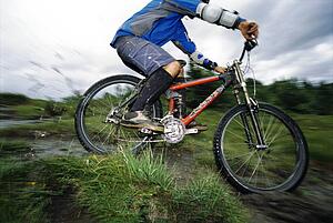 Man outdoors on trails riding bicycle (selective focus)