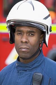 Fireman standing by fire engine wearing helmet