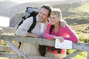 Couple on cliffside outdoors leaning on railing and smiling