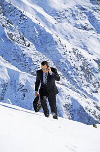 Businessman outdoors on snowy mountain using cellular phone