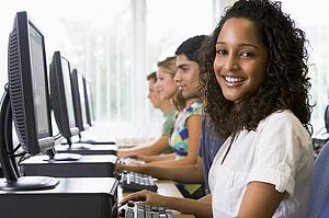 Four people sitting at computer terminals (depth of field/high key)