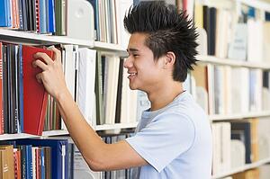 Man in library pulling book off a shelf (depth of field)