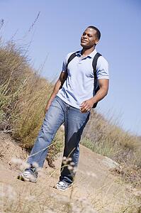 Man walking a trail in the countryside.