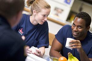 Three firefighters in break room drinking coffee and talking (selective focus)