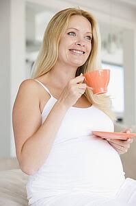 Pregnant woman with cup of tea smiling