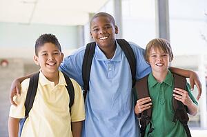 Three students standing outside school together smiling (high key)