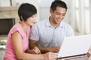 Couple in dining room with laptop smiling