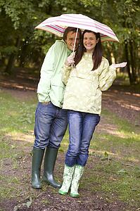 Couple outdoors in rain with umbrella smiling