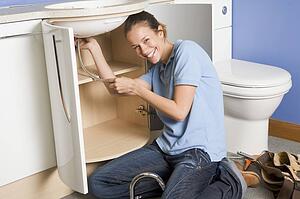Plumber working on sink smiling