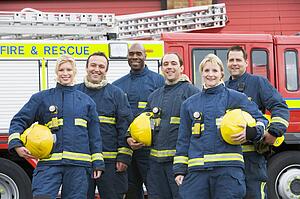Six firefighters standing by fire engine