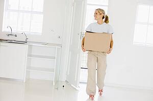 Woman with box moving into new home smiling